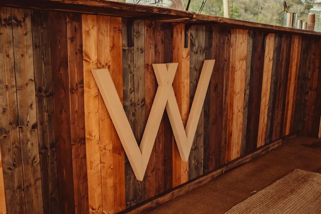 Rustic timber bar with the Woodhill W monogram at Woodhill dry hire wedding venue, Faversham, Kent