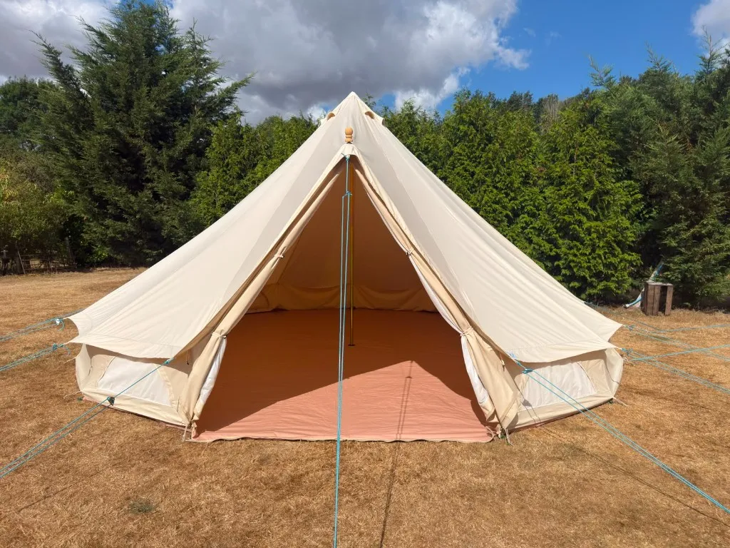 An open cream bell tent showing the tan groundsheet inside at Woodhill Campsite, Faversham, Kent