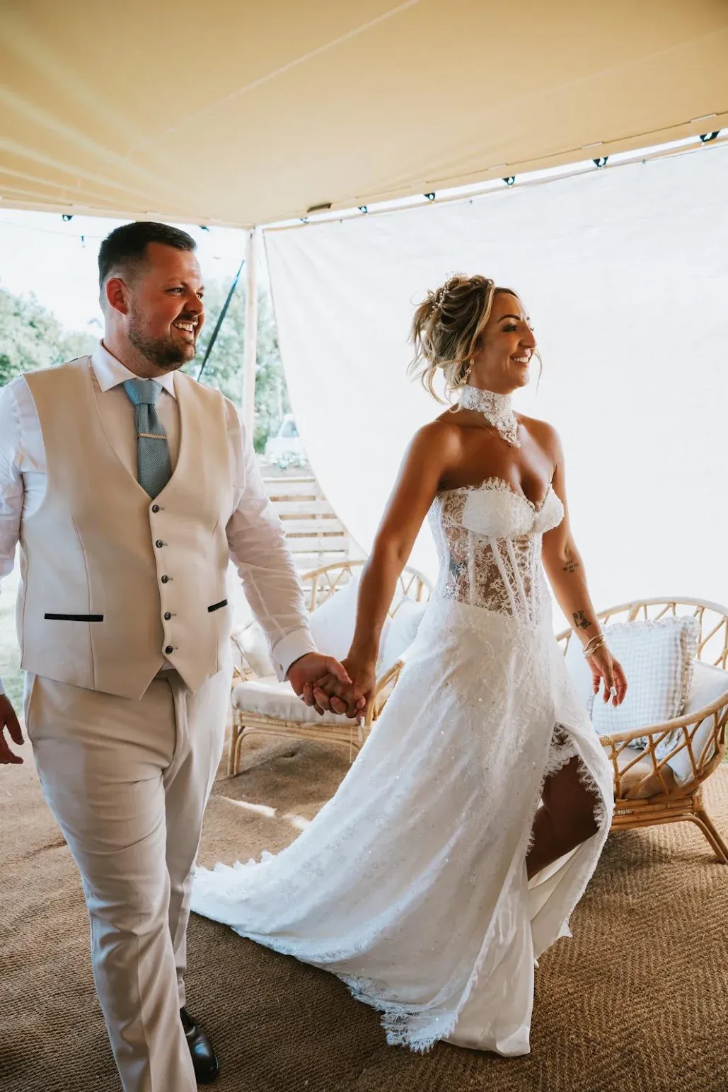 A bride and groom hand in hand under the Bedouin stretch tent at Woodhill Weddings, Faversham, Kent