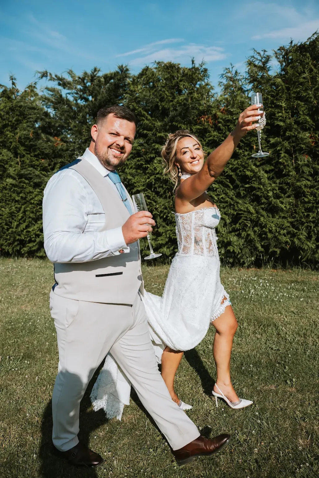 A bride and groom raising a champagne toast in the grounds at Woodhill Weddings, Faversham, Kent